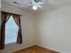 Cozy bedroom features a window with curtains, neutral walls, wood floor, and a ceiling fan at 233 Melody Gardens Dr., Surfside Beach, SC 29575