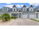 Charming blue two-story townhouse featuring a well-manicured lawn and attached garages under a bright blue sky at 413 Goldenrod Circle # 2B, Little River, SC 29566