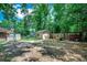 Backyard with storage sheds, a fire pit, and a partial fence under a canopy of trees at 4189 Schoolhouse Circle, Little River, SC 29566