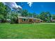 Well-maintained brick home with a large front lawn and mature trees in the background at 4189 Schoolhouse Circle, Little River, SC 29566