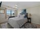 Bright bedroom with a queen bed, ceiling fan, and view from the window. Furnished with lamps and black furniture at 5511 N Ocean Blvd. # 1801, Myrtle Beach, SC 29577