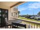 Balcony view with a table and chairs looking towards a grass area, parking lot, palm trees, and ocean in the background at 5601 N Ocean Blvd. # E-113, Myrtle Beach, SC 29577
