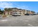 Exterior daytime shot of parking area with condo buildings, blue sky and palm trees at 5601 N Ocean Blvd. # E-113, Myrtle Beach, SC 29577