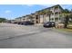 Exterior view of condo building with ample parking and tropical landscaping on a bright sunny day at 5601 N Ocean Blvd. # E-113, Myrtle Beach, SC 29577