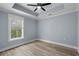 Cozy bedroom with light gray walls, a ceiling fan, tray ceiling and natural light filtering through the window at 6001-Mh13A S Kings Hwy., Myrtle Beach, SC 29575