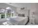Light-filled bedroom with large windows, white furniture, and decorative pillows at 695 Riverwalk Dr. # 101, Myrtle Beach, SC 29579