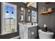 Well-lit half bathroom with a vanity, toilet, and framed mirrors complementing hanging plants near the window at 752 Hobonny Loop, Longs, SC 29568