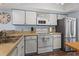 A bright kitchen featuring white cabinets, a white oven, a stainless fridge, and a stainless steel sink at 81 Shadow Moss Pl. # 81, North Myrtle Beach, SC 29582
