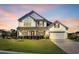 Charming two-story home with white siding, inviting front porch, manicured lawn, and attached two-car garage at 932 Abernathy Place, Surfside Beach, SC 29575