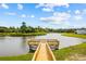 Scenic view of a wooden dock extending into the lake, surrounded by lush greenery and a blue sky at 1016 Laurens Mill Dr., Myrtle Beach, SC 29579