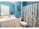 Bathroom featuring blue walls, shower with floral curtain, and a single sink with storage below at 1301 Camlet Ln., Little River, SC 29566