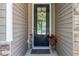 Close-up of a black front door with glass window and seasonal wreath; pot of red flowers to the side at 1301 Camlet Ln., Little River, SC 29566