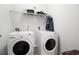 Bright laundry room with white front load washer and dryer and wire shelving for storage space at 1301 Camlet Ln., Little River, SC 29566