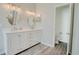 Bright bathroom featuring a double vanity with matching oval mirrors and wood look flooring at 1409 Ashwood Circle, Surfside Beach, SC 29575