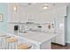 Bright kitchen featuring white cabinets, white appliances, bar seating and wood-look flooring at 4105 S Ocean Blvd. # 102, North Myrtle Beach, SC 29582