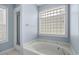 Well-lit bathroom featuring a soaking tub, a glass block window, and separate shower at 4162 Dupree Dr., Little River, SC 29566