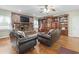 Spacious living room with a brick fireplace, built-in wooden bookshelves, and comfortable leather chairs at 4691 Mill Pond Rd., Murrells Inlet, SC 29576