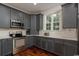 Well-lit kitchen featuring stainless steel appliances, gray cabinets, white countertops, and hardwood floors at 4986 Salt Creek Ct., North Myrtle Beach, SC 29582