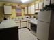 Cozy kitchen featuring a breakfast bar, white appliances, and bright yellow walls at 500 Fairway Village Dr. # 4-F, Myrtle Beach, SC 29588