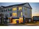 Beautiful three-story townhome with warm lighting and a well-manicured lawn at dusk at 8468 Duke Pl. # 28, Myrtle Beach, SC 29572