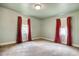 Spacious bedroom featuring neutral-toned walls, plush carpeting, and a window dressed with red curtains at 1024 Palmetto St., Georgetown, SC 29440