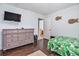 Bedroom featuring a dresser, TV, wood floors, tropical leaf comforter, and a view to another room at 121B 7Th Ave. S, Surfside Beach, SC 29575