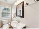 Well-lit bathroom with a pedestal sink, framed mirror, and a window with blinds at 126 Cleland St., Georgetown, SC 29440