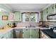 A charming kitchen with green cabinets, stainless steel appliances, and view to the outside at 1272 Park Hill Dr., Conway, SC 29526
