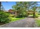 A brick home with a car port and a gravel driveway framed by mature trees and landscaping at 1272 Park Hill Dr., Conway, SC 29526