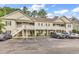 Inviting two-story condo building with light beige siding, balconies, green shutters, and ample parking spaces at 160 Lazy Willow Ln. # 202, Myrtle Beach, SC 29588