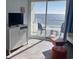 Bright condo living room with ocean view, balcony access, with a gray dresser and television at 201 S Ocean Blvd. # 408, Myrtle Beach, SC 29577