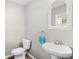 A simple half bathroom with a pedestal sink, toilet, and decorative mirror with a woven frame at 317 Truce St., Myrtle Beach, SC 29588