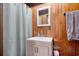 Rustic bathroom featuring wood paneling, white vanity and toilet, with a curtain shower at 325 Orange St., Georgetown, SC 29440