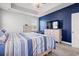 Bright bedroom with a blue accent wall, flat-screen TV, and a comfortable striped bed at 405 Spring View Ct., Little River, SC 29566