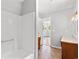 Bathroom featuring a white bathtub with enclosure and view into bedroom with wood-look floor at 4249 E Highway 9, Loris, SC 29569