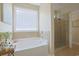 Bathroom featuring a glass shower, a soaking tub, and a large window at 428 Arlington Circle, Murrells Inlet, SC 29576