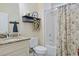 A cozy bathroom features a shower with decorative curtain, granite vanity top, and decorative shelving unit at 428 Arlington Circle, Murrells Inlet, SC 29576