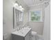 This bathroom has a window, toilet, and vanity with a grey cabinet, along with a shower behind a curtain at 4325 Ellis Ave., Little River, SC 29566