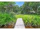 A wooden backyard dock leads the eye towards a cozy home and firepit, framed by vibrant greenery at 485 Waterford Dr., Georgetown, SC 29440