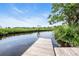 Picturesque view of a private wooden dock extending into a calm canal, under a clear sky with scattered clouds at 485 Waterford Dr., Georgetown, SC 29440