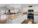 Open kitchen features white cabinets, stainless appliances and breakfast bar, leading to the living area at 4872 Dahlia Ct. # 305, Myrtle Beach, SC 29577