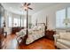A serene main bedroom features a four-poster bed, hardwood floors, and bay windows at 492 Grand Cypress Way, Murrells Inlet, SC 29576