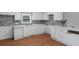 Bright kitchen features stone backsplash, white cabinetry, and wood-look flooring at 5 Dogwood St., Hemingway, SC 29554