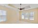 Bright bedroom features neutral carpet, a tray ceiling with fan, and an abundance of natural light from three large windows at 56 Willowbend Dr., Murrells Inlet, SC 29576