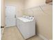 Clean laundry room features a washer, dryer, tiled floor, and a door to the outside with access to shelving at 56 Willowbend Dr., Murrells Inlet, SC 29576