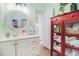 Charming bathroom with a decorative round mirror, vanity with drawers, and a red cabinet for linen storage at 6001-R11 S Kings Hwy., Myrtle Beach, SC 29575