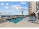 Community outdoor pool near the beach with chairs, palm trees, and ocean views at 920 N Waccamaw Dr. # 2310, Murrells Inlet, SC 29576