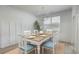 Bright dining room featuring paneled walls, a modern chandelier and a wooden table with blue chairs at 964 Irving Dr., Little River, SC 29566