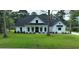 Inviting two-story modern farmhouse exterior with white siding, dark roof, manicured lawn, and columned front porch at 1464 Hawthorn Dr., Pawleys Island, SC 29585
