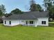 Rear exterior showcasing the home's white siding, dark roof, and a covered patio overlooking the grassy lawn at 1464 Hawthorn Dr., Pawleys Island, SC 29585